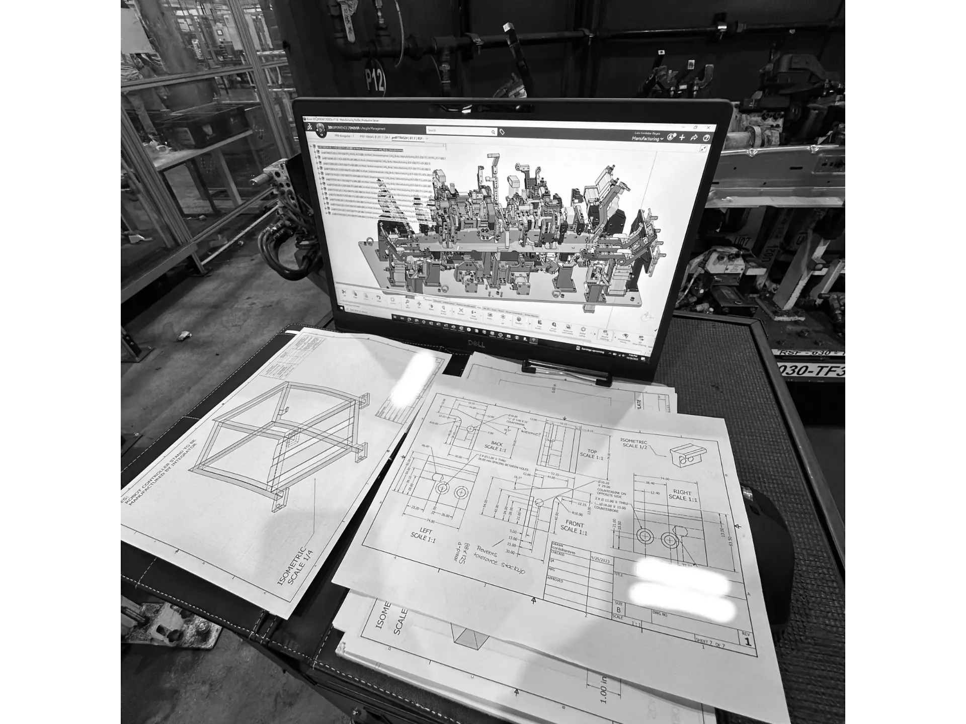 CAD model and engineering drawings on a laptop in a manufacturing shop